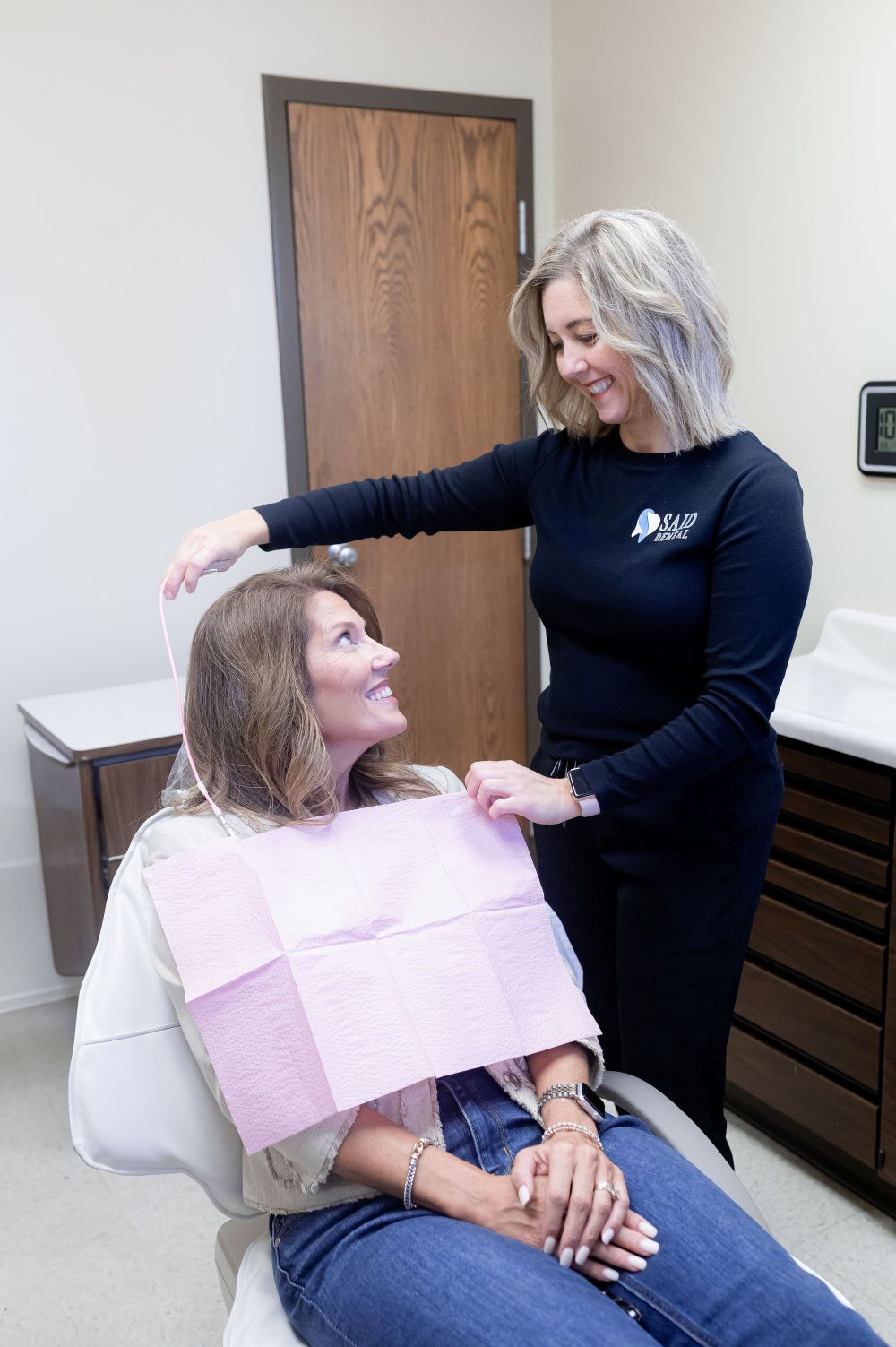 dental professional adjusting patient bib in modern clinic